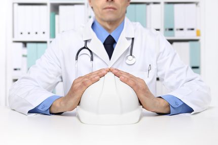 Mediziner hält einen Bauhelm in den Händen