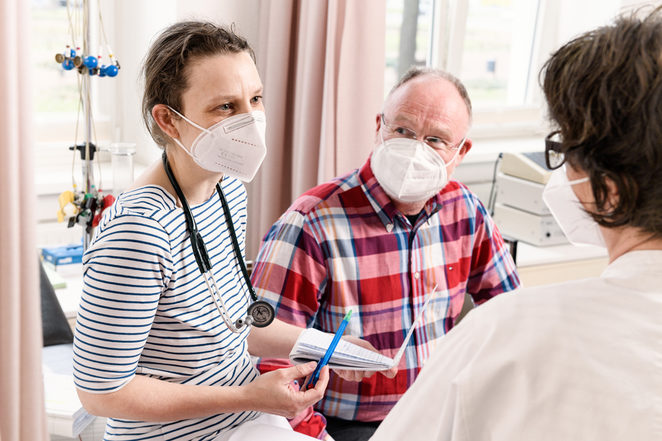 Junge Ärztin mit Patient und anderer Ärztin