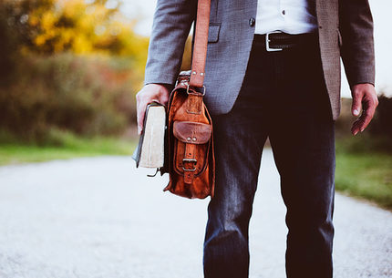 Mann mit Buch und Tasche auf Landstrasse