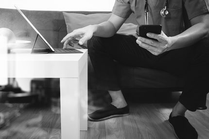 Medical and Health context,doctor hand working with smart phone,digital tablet computer,stethoscope,sitting on sofa in living room,black and white